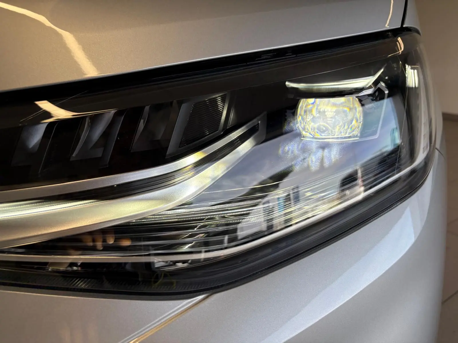 Gros plan sur le phare avant droit du Volkswagen Caddy 2025 gris argent, mettant en valeur son design moderne et lumineux.