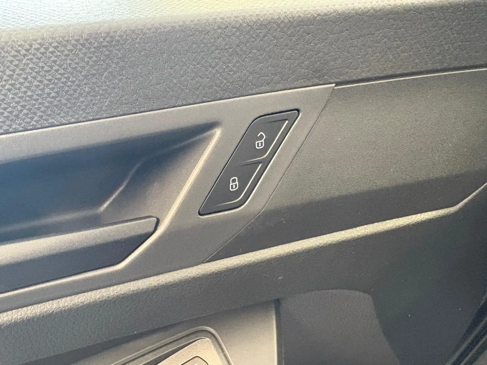 Gros plan sur la commande de verrouillage des portes côté intérieur d'une Volkswagen Caddy gris argent 2025.