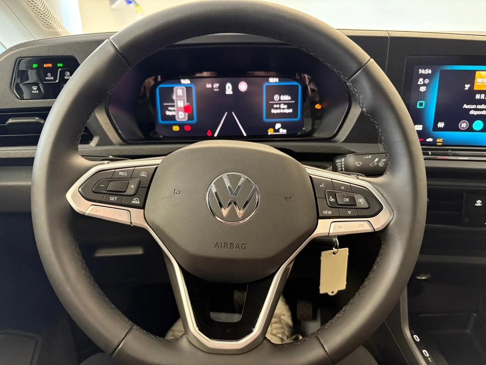 Vue rapprochée du volant noir du Volkswagen Caddy 2025 avec tableau de bord numérique et commandes intégrées.