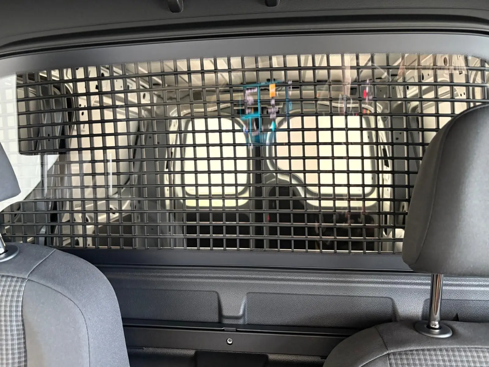 Vue intérieure arrière du Volkswagen Caddy gris argent 2025, montrant la grille de séparation entre cabine et espace de chargement.