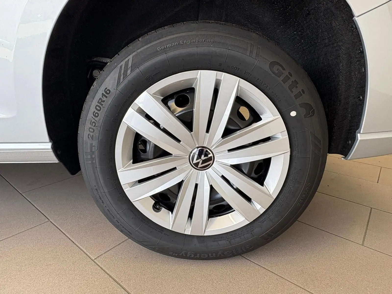 Gros plan sur la roue avant droite d'un Volkswagen Caddy gris argent 2025 avec jante en alliage et pneu Giti.