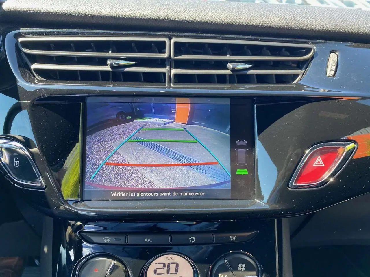 Écran tactile central affichant la caméra de recul dans l'habitacle d'une DS3 rouge toit blanc, tableau de bord noir brillant.