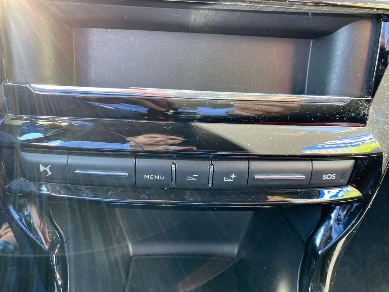 Boutons de commande du système audio et SOS sur la console centrale brillante d'une DS3 rouge toit blanc vue de face.