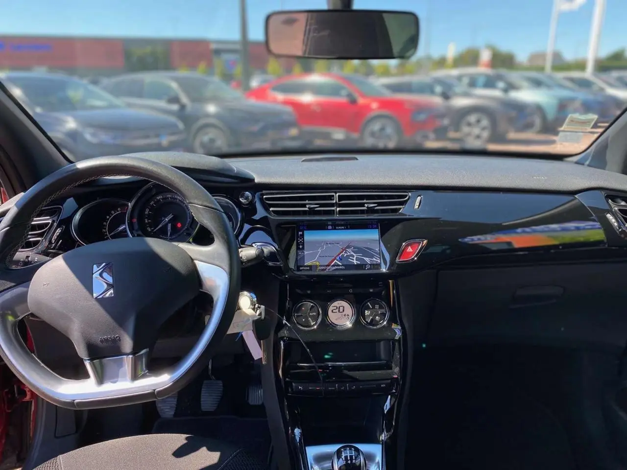 Vue intérieure avant du tableau de bord de la DS3 rouge avec toit blanc, affichage navigation tactile et volant DS.