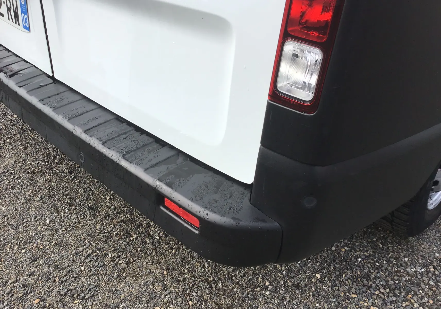 Gros plan sur le coin arrière droit blanc du Renault Trafic Fourgon 2022 avec feu arrière et pare-chocs noir.