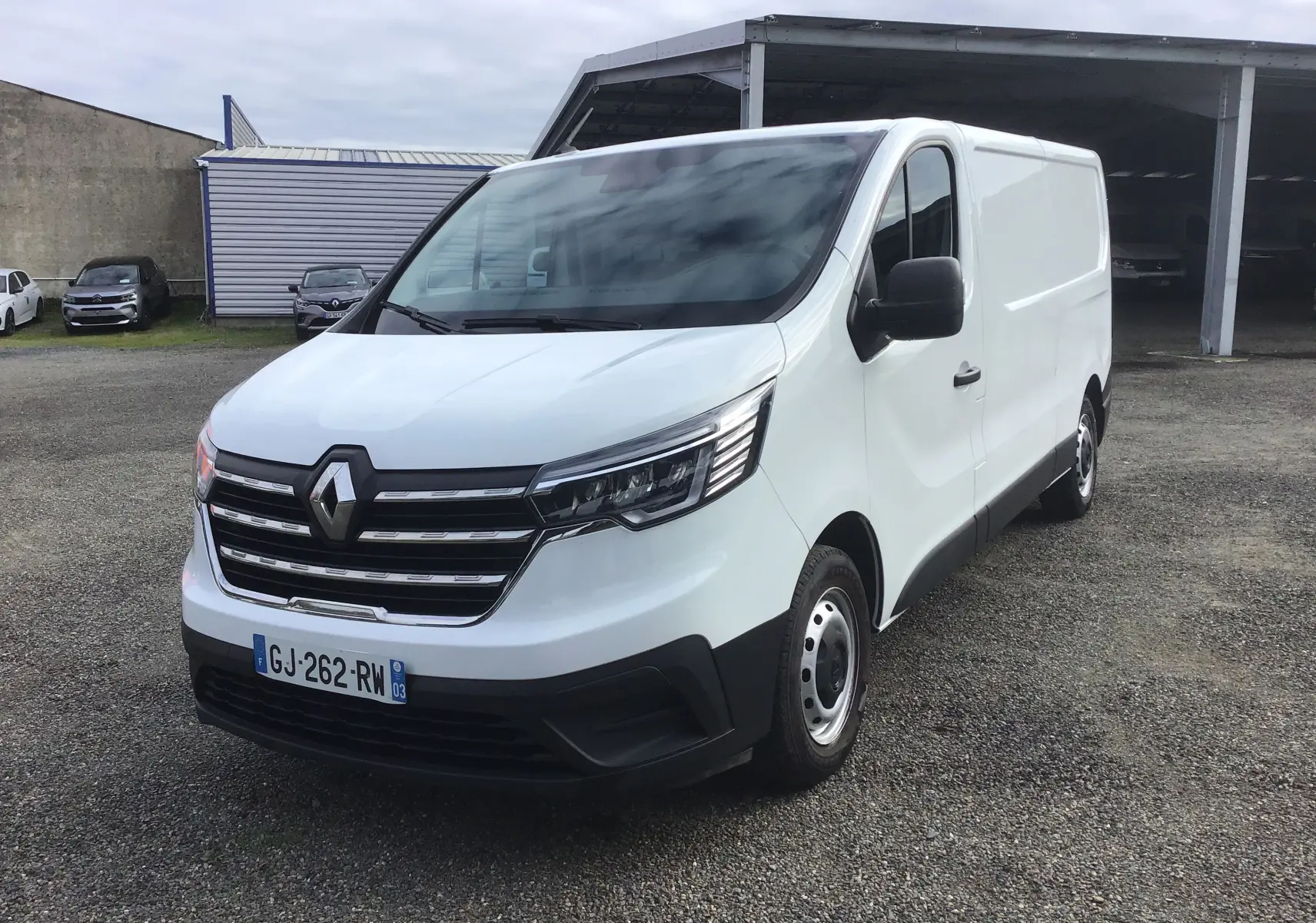 Renault Trafic Fourgon blanc vu en 3/4 avant droit, avec calandre chromée et phares LED modernes.