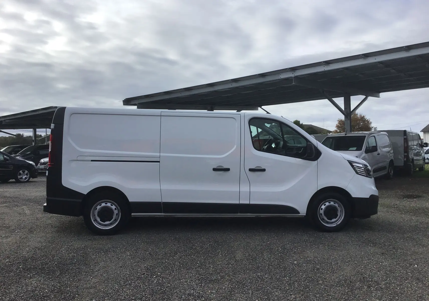 Vue de profil côté gauche d'un Renault Trafic Fourgon blanc 2022 avec portes latérales et jantes acier noires.