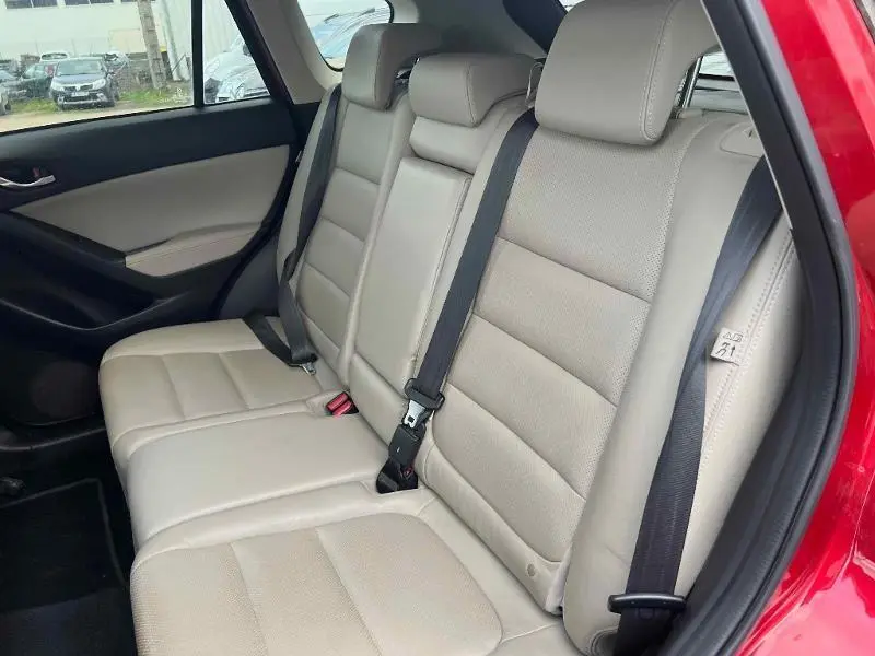 Vue côté droit sur la banquette arrière cuir beige du Mazda CX-5 Soul Red Métallisé avec ceintures de sécurité visibles.