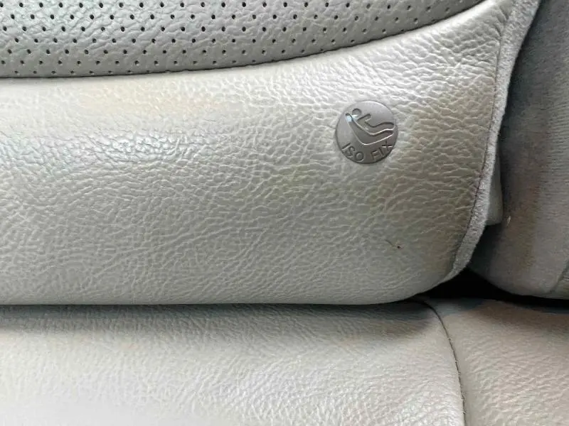 Gros plan sur l'icône ISOFIX sur la sellerie cuir gris clair du siège arrière d'un Mazda CX-5 Soul Red Métallisé.