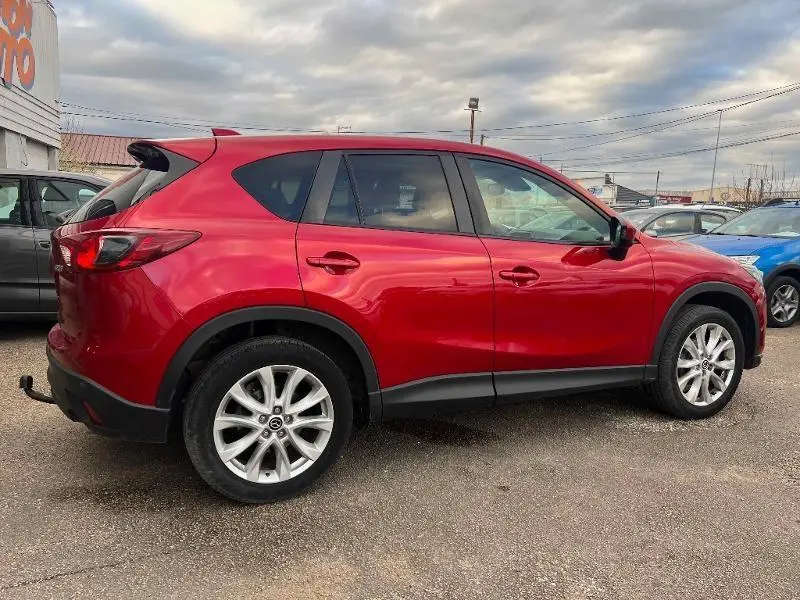 Vue latérale droite d'un Mazda CX-5 rouge Soul Red Métallisé avec jantes alu 19 pouces et attelage arrière.