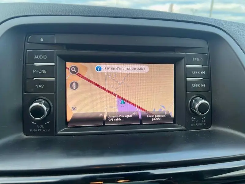 Vue rapprochée de l'écran GPS multifonction du tableau de bord du Mazda CX-5, avec commandes autour.