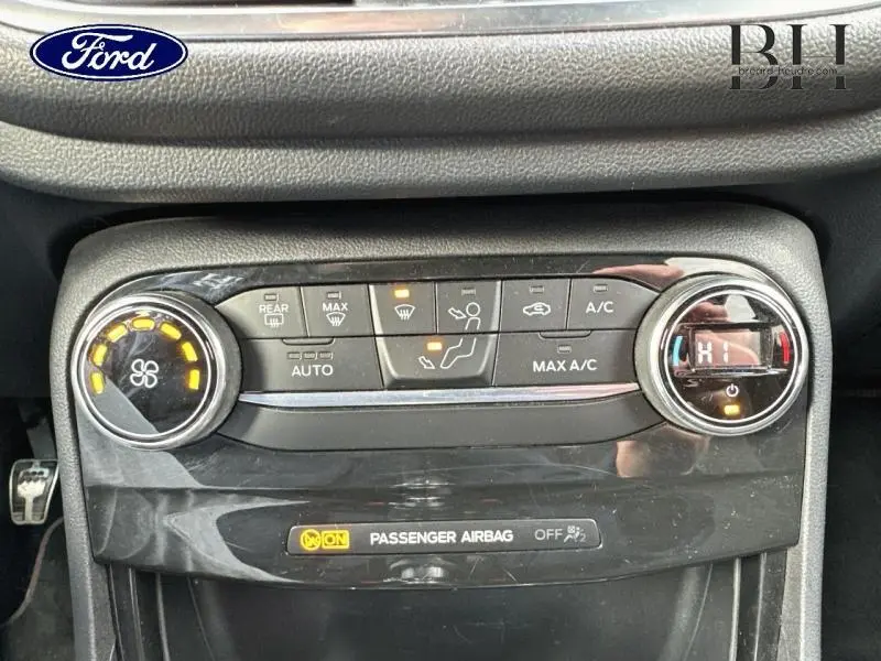 Vue rapprochée du tableau de bord noir du Ford Puma 2020, montrant les commandes de climatisation et l'indicateur d'airbag passager.