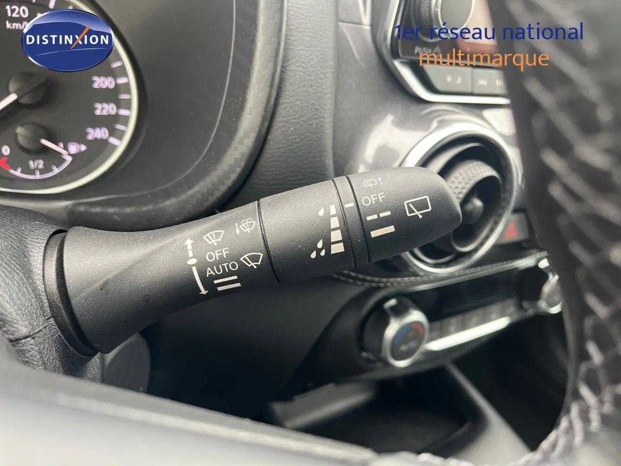 Gros plan sur la commande d’essuie-glace à gauche du volant dans l’habitacle du Nissan Juke blanc nacré 2024.