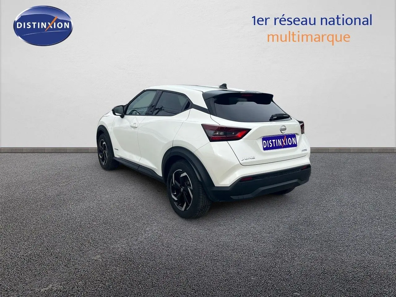 Vue 3/4 arrière droite du Nissan Juke blanc nacré métallisé 2024 avec jantes noires et vitres teintées.