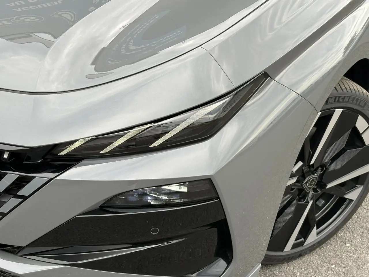Gros plan sur l'avant droit gris Sélénium du Peugeot 308 SW avec phares LED et jante alliage bi-tons.