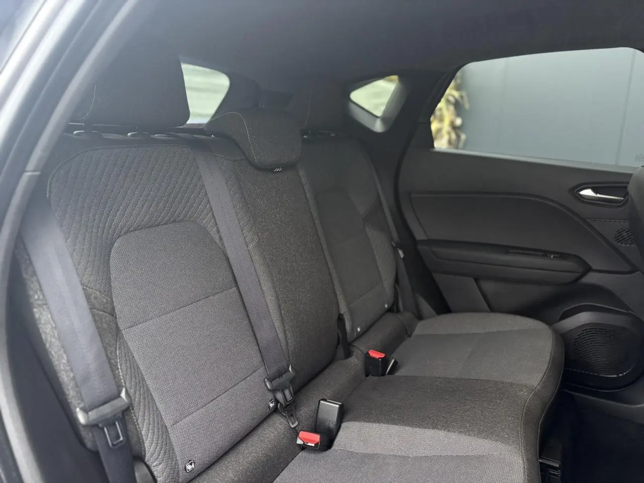 Vue intérieure sur les sièges arrière gris foncé du Renault Captur TCE 100 Techno avec ceintures et appuie-têtes visibles.