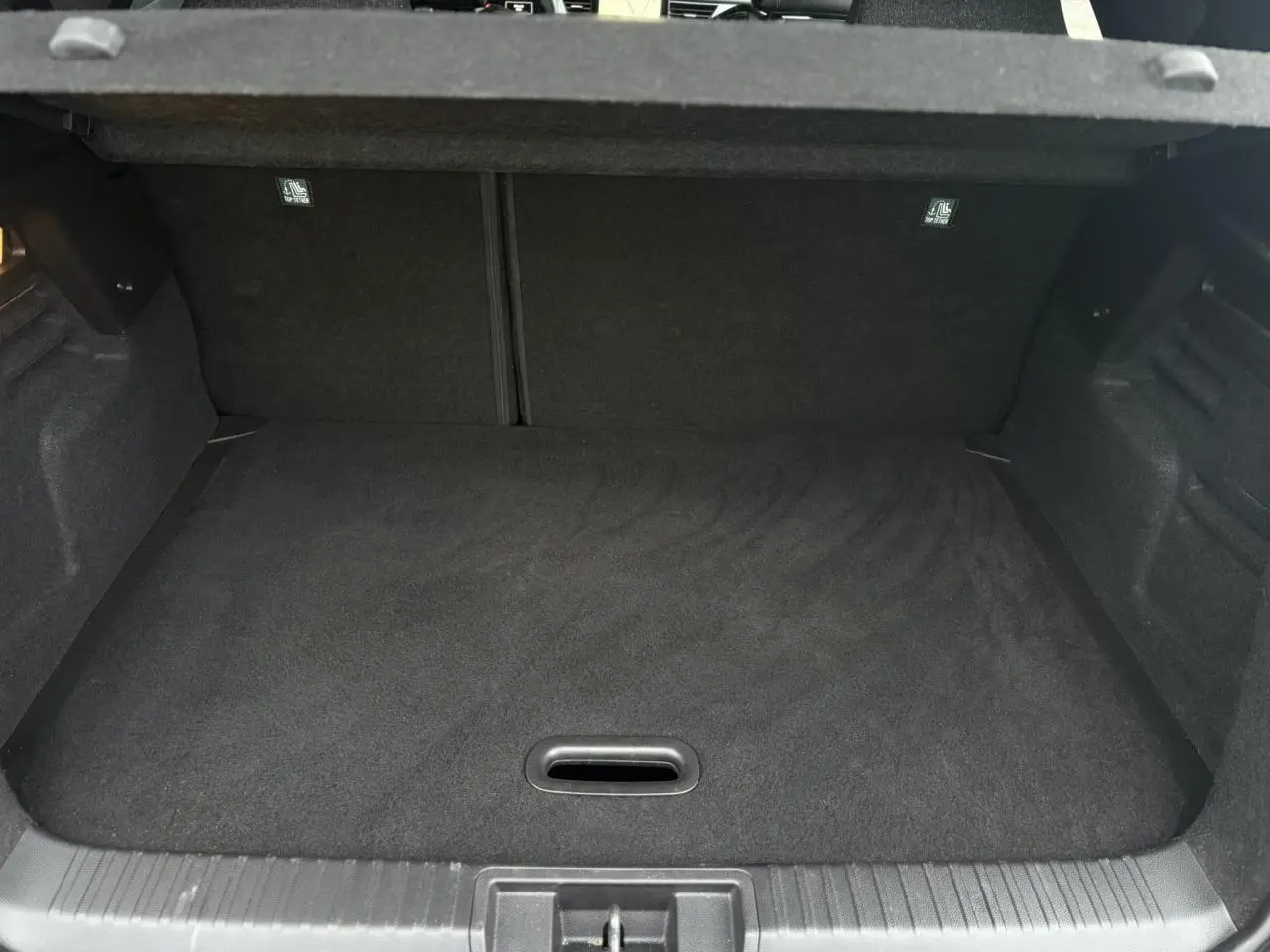 Vue intérieure du coffre spacieux et plat du Renault Captur TCE 100 Techno 2025, revêtement noir uniforme.
