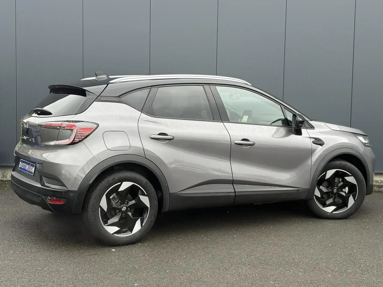 Vue latérale droite d'un Renault Captur 2025 gris Cassiopée avec toit noir et jantes alu 18 pouces diamantées noires.
