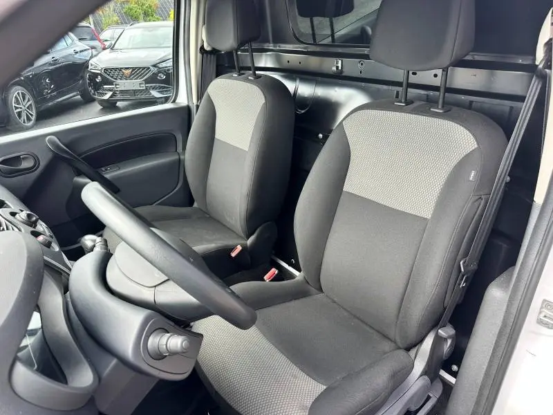 Intérieur du Renault Kangoo Express électrique 2022 montrant les sièges avant gris et la cloison tubulaire noire derrière.