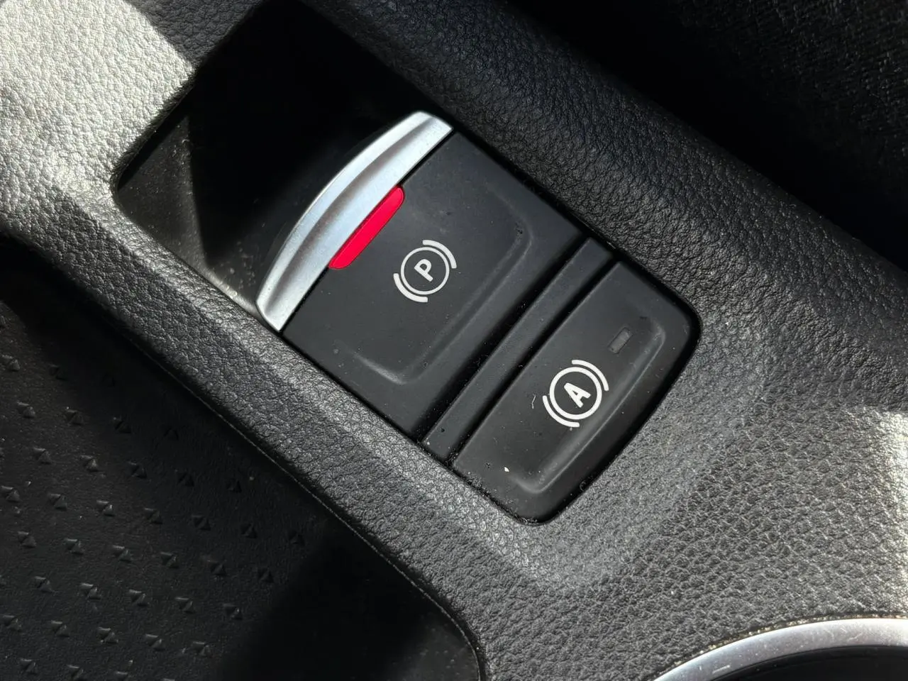 Gros plan sur les boutons du frein de parking électrique et de l'arrêt automatique dans l'habitacle du Renault Captur E-Tech rouge.