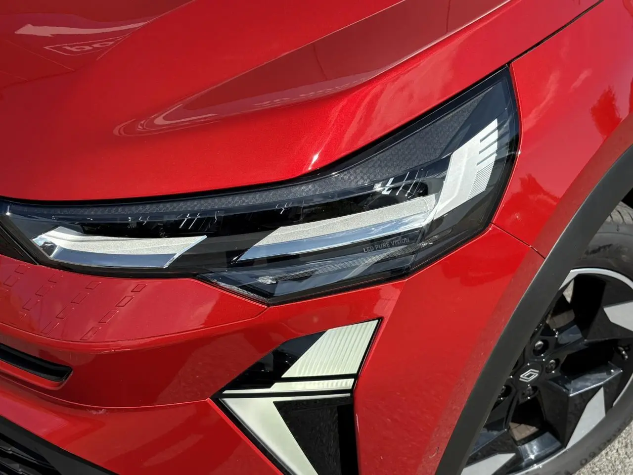 Gros plan sur le phare avant droit LED Pure Vision et la roue noire à jante aluminium du Renault Captur Rouge Désir.