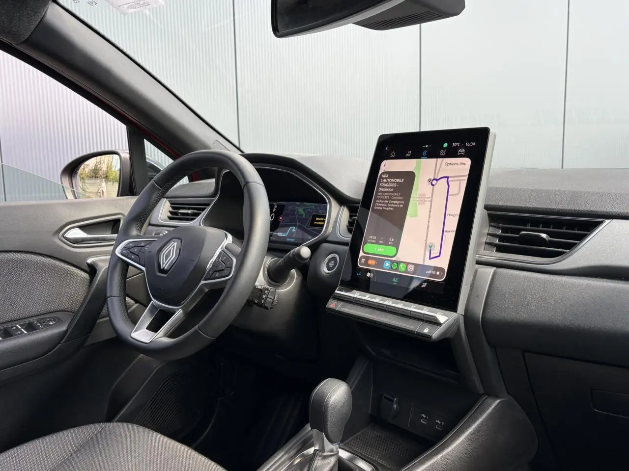 Vue intérieure côté conducteur du Renault Captur E-Tech 2025, avec écran tactile vertical et volant multifonctions noir.