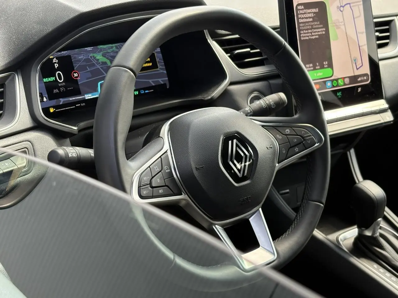 Vue rapprochée du volant cuir multifonctions et tableau de bord numérique du Renault Captur E-Tech 2025.