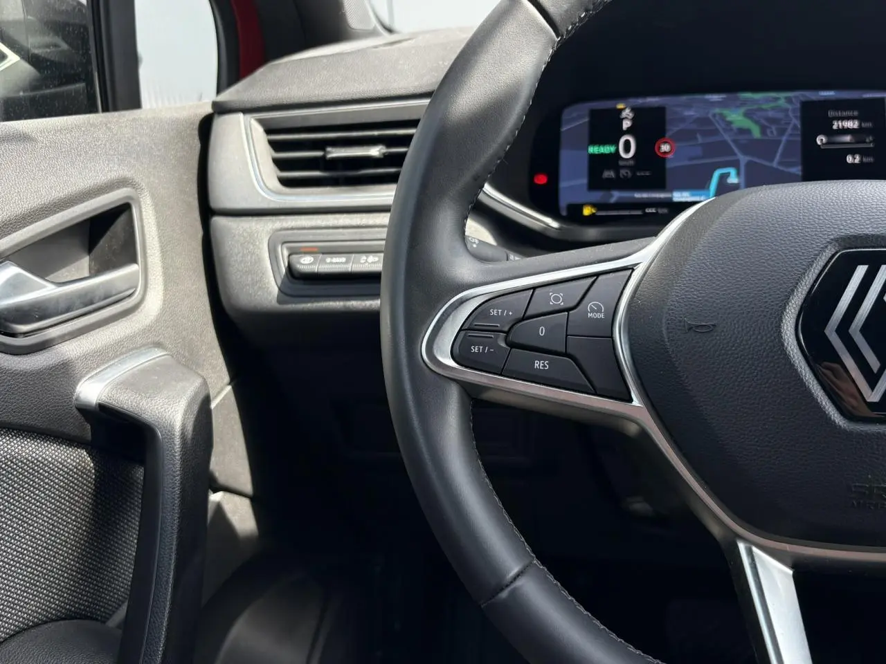 Gros plan sur le volant cuir multifonctions et le tableau de bord numérique du Renault Captur E-Tech 2025.