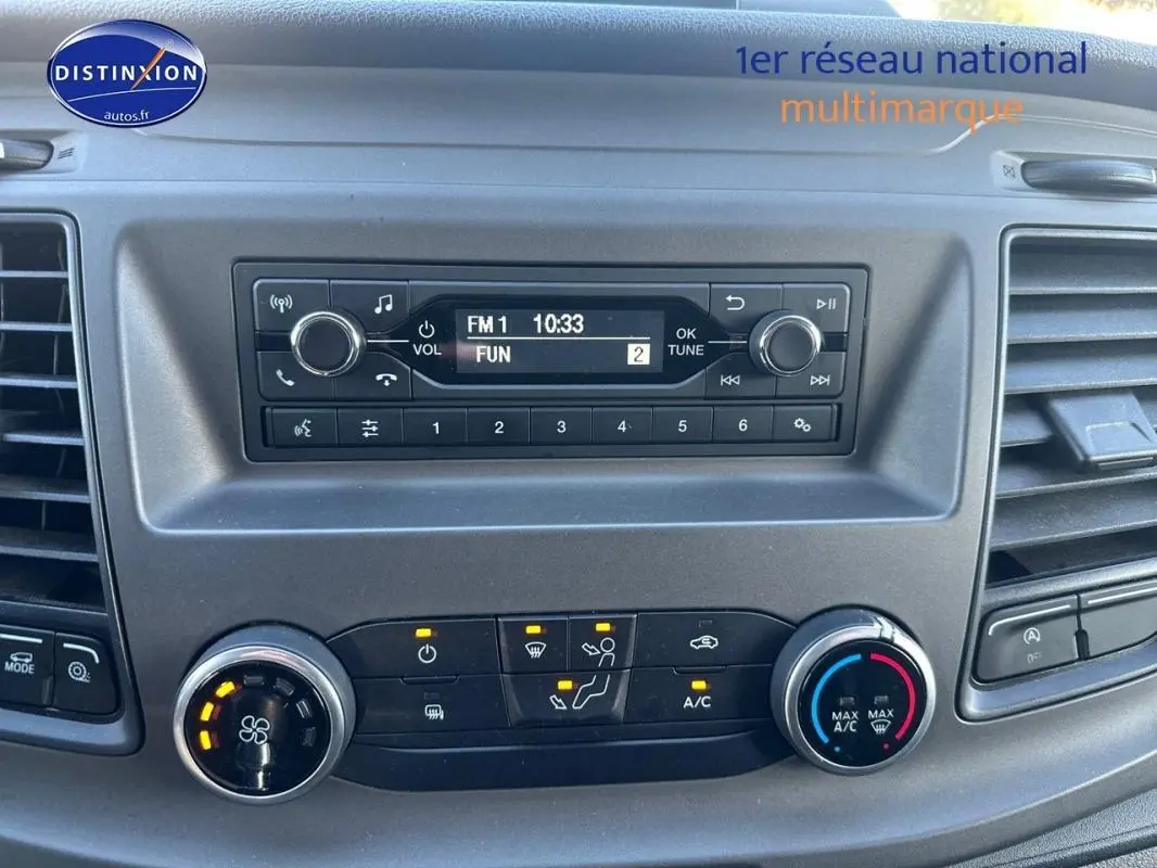 Tableau de bord du Ford Transit Custom blanc 2021, vue frontale centrée sur la radio et les commandes de climatisation.