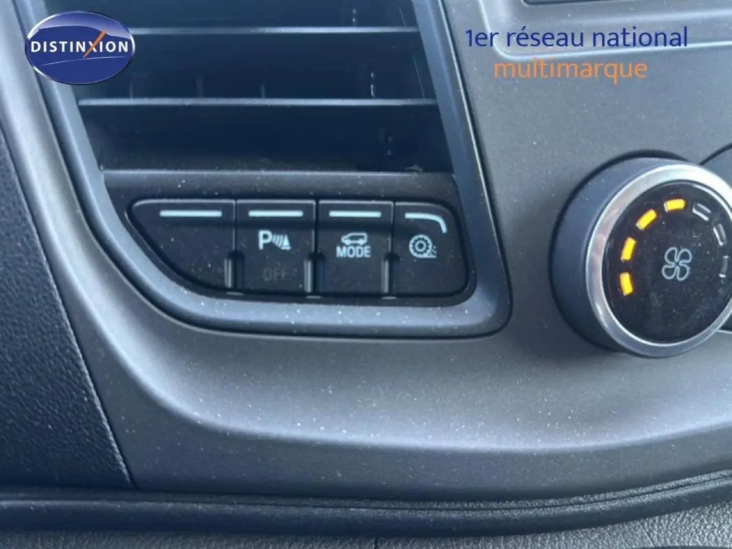 Détail du tableau de bord du Ford Transit Custom blanc 2021, montrant les boutons de réglage et la molette de ventilation.