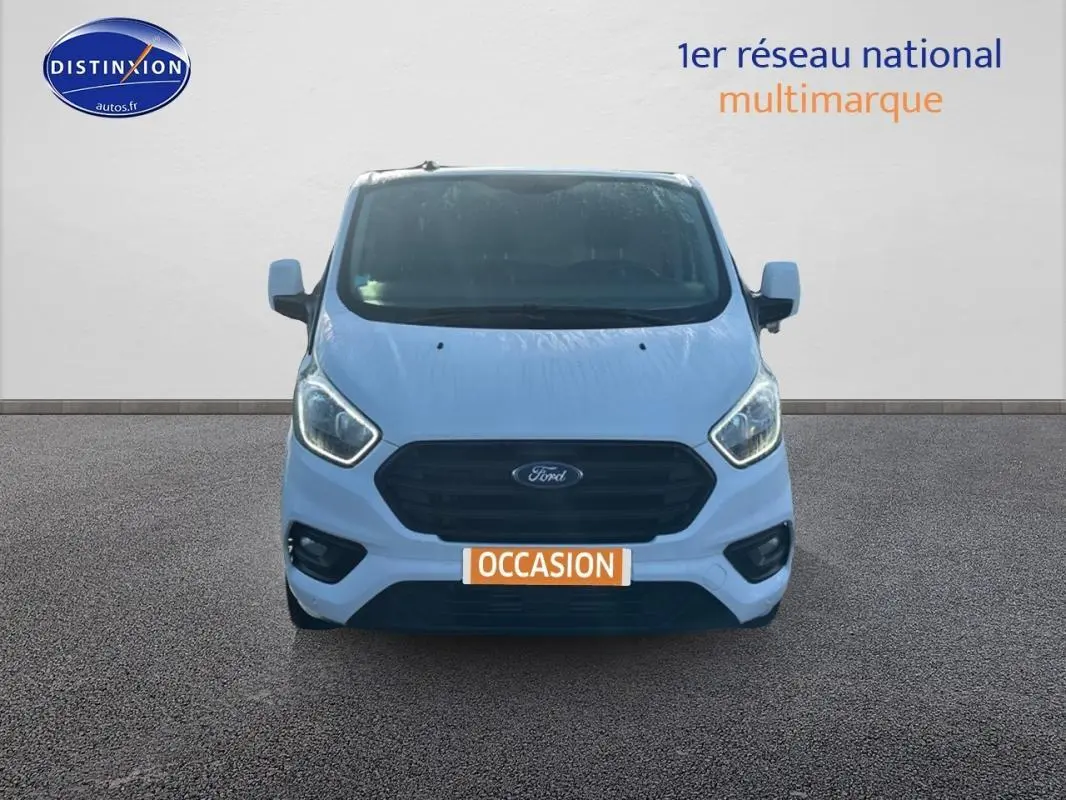 Vue avant d’un Ford Transit Custom fourgon blanc 2021 avec calandre noire et plaque « OCCASION » visible.