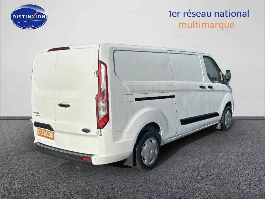 Vue 3/4 arrière droite d’un Ford Transit Custom blanc, fourgon utilitaire avec porte latérale et vitres surteintées.