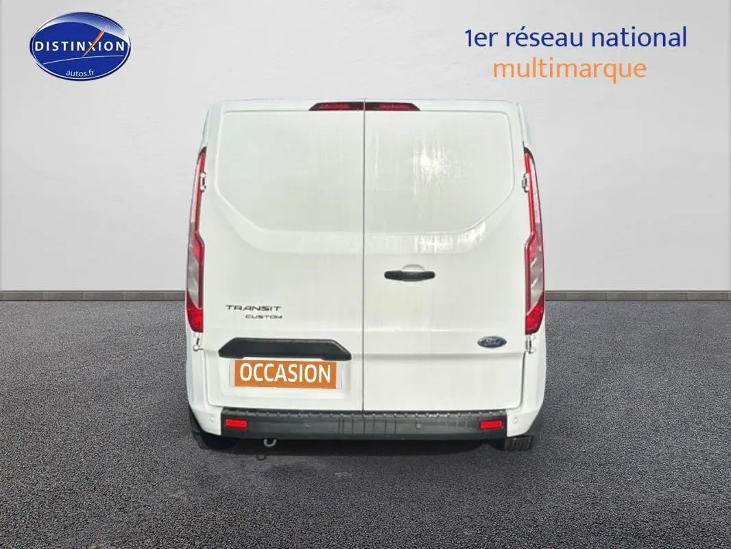 Vue arrière d'un Ford Transit Custom blanc avec portes battantes et plaque "OCCASION" visible.