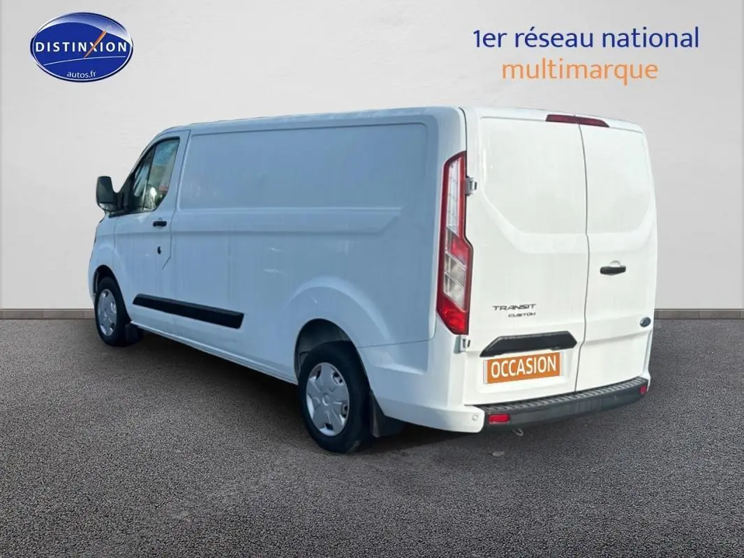 Vue 3/4 arrière droite d’un Ford Transit Custom blanc, fourgon utilitaire avec porte latérale et vitres surteintées.