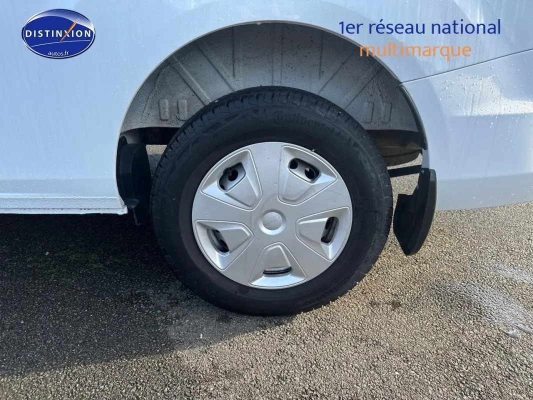 Gros plan sur la roue arrière droite d’un Ford Transit Custom blanc avec enjoliveur et garde-boue noir.