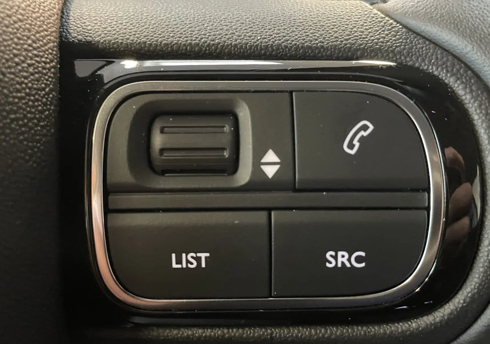 Gros plan sur les commandes noires du volant côté gauche du Citroën C5 Aircross 2024, avec boutons list, SRC et appel.