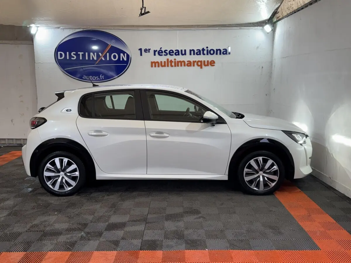 Peugeot 208 électrique blanche vue de profil côté gauche, avec jantes alliage et toit noir contrasté.