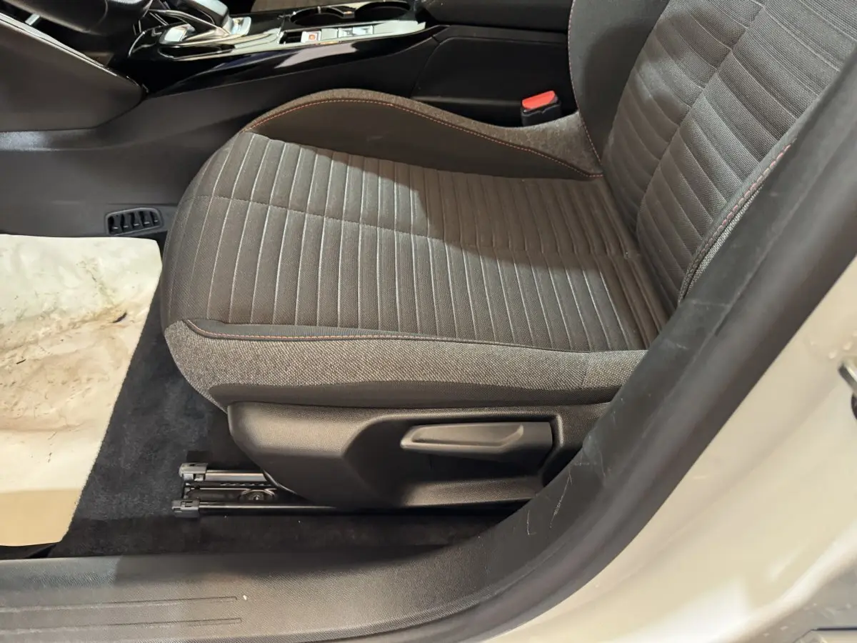Vue latérale du siège avant droit gris foncé avec surpiqûres rouges dans l'habitacle d'une Peugeot 208 électrique 2020.