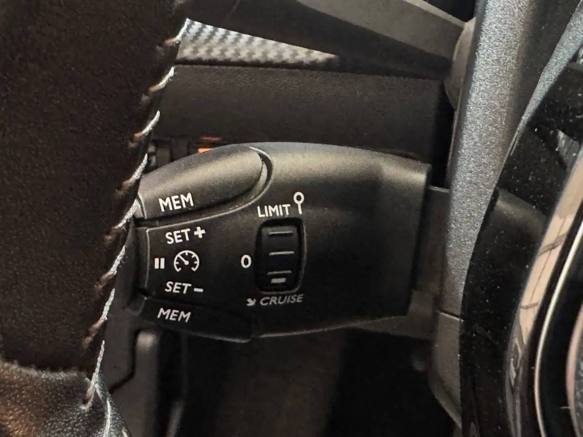 Gros plan sur la commande de régulateur de vitesse au volant cuir de la Peugeot 208 électrique Active Business.