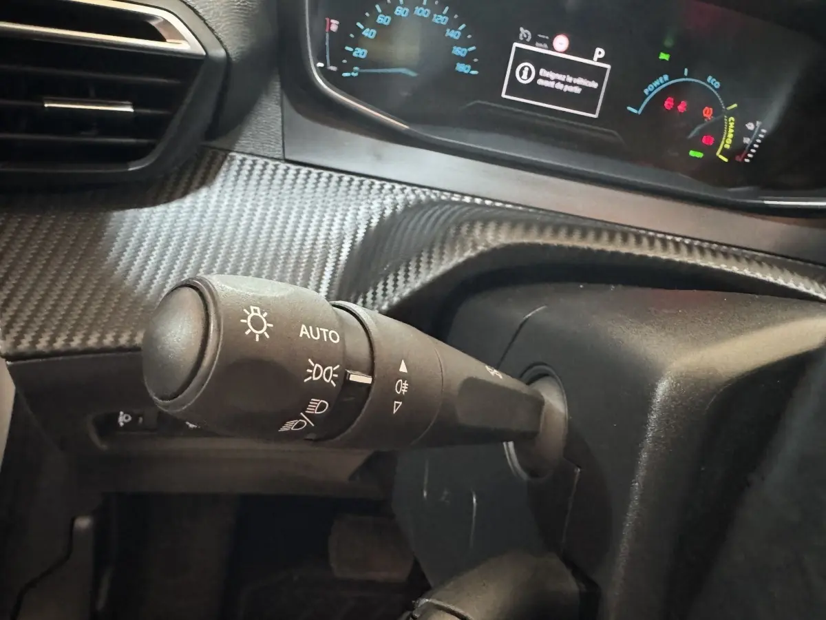 Gros plan sur la commande des phares à gauche du volant dans l’habitacle du Peugeot 208 électrique Active Business 2020.