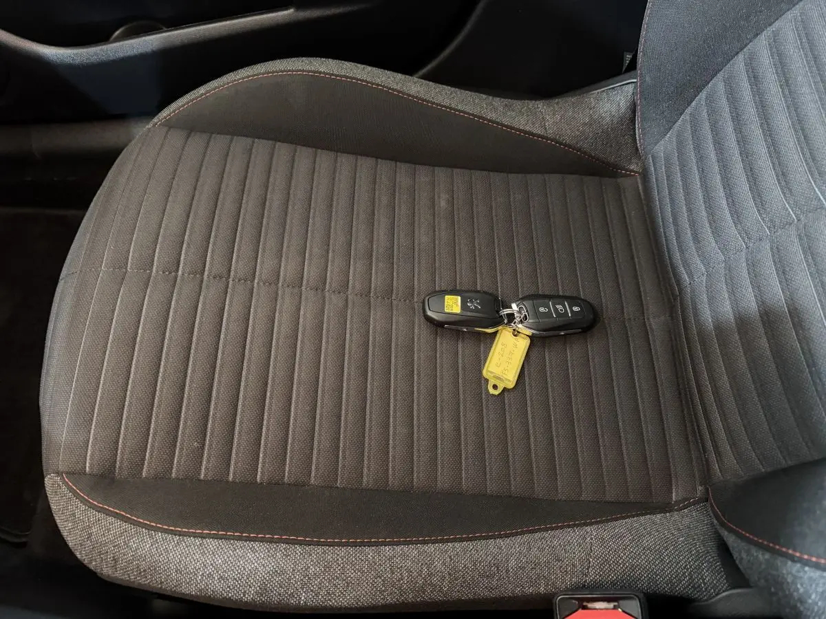 Gros plan sur la banquette arrière grise de la Peugeot 208 électrique avec les clés posées dessus.