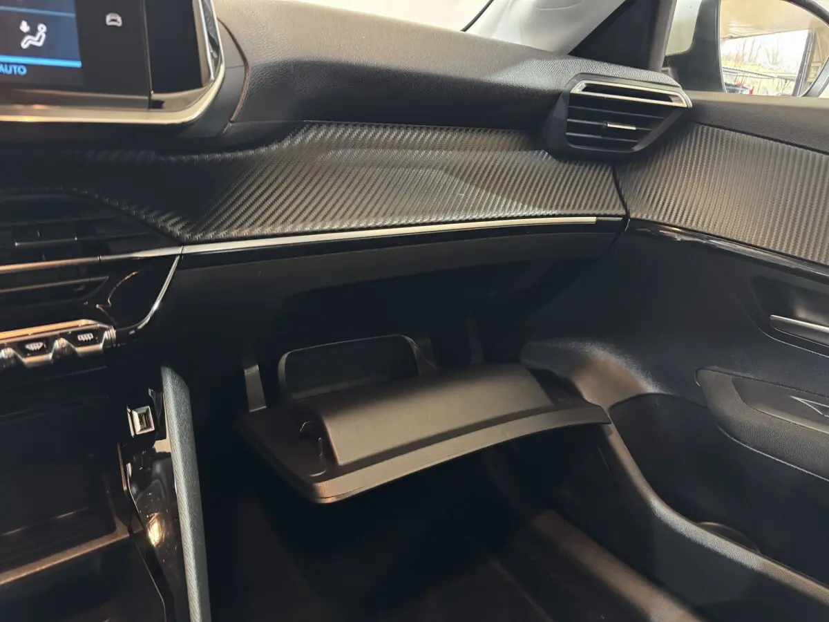 Intérieur côté passager de la Peugeot 208 électrique 2020, tableau de bord noir avec boîte à gants ouverte.