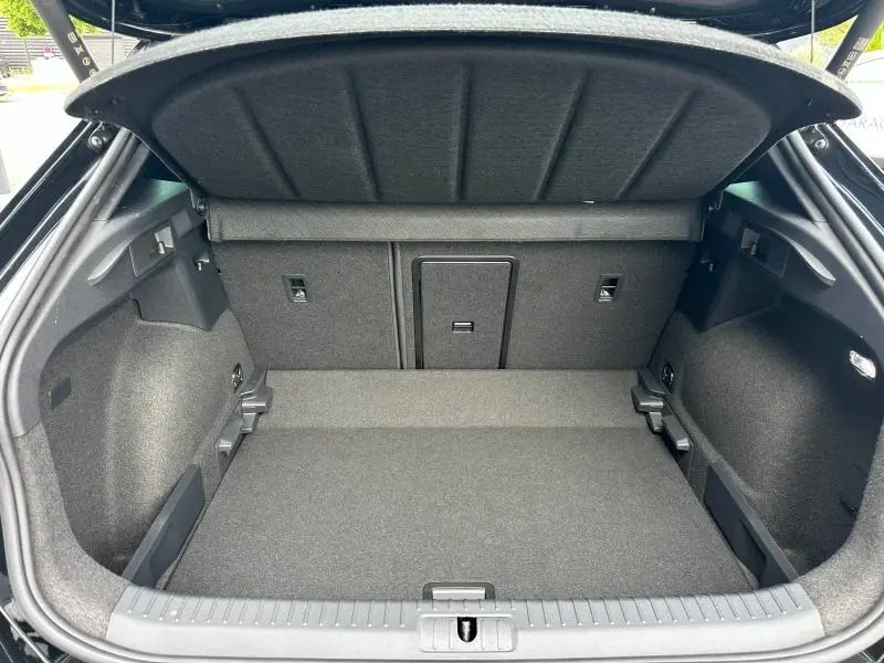 Coffre ouvert vu de l'arrière du CUPRA Formentor noir Minuit, montrant un espace de chargement propre et bien fini.