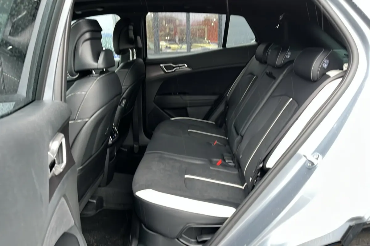 Vue intérieure arrière côté gauche du Kia Sportage 2026 gris perle, sièges noirs avec surpiqûres blanches.