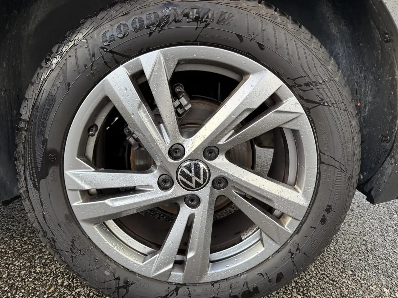 Gros plan sur la jante alliage léger Valencia grise avec logo Volkswagen au centre, pneu Goodyear mouillé.