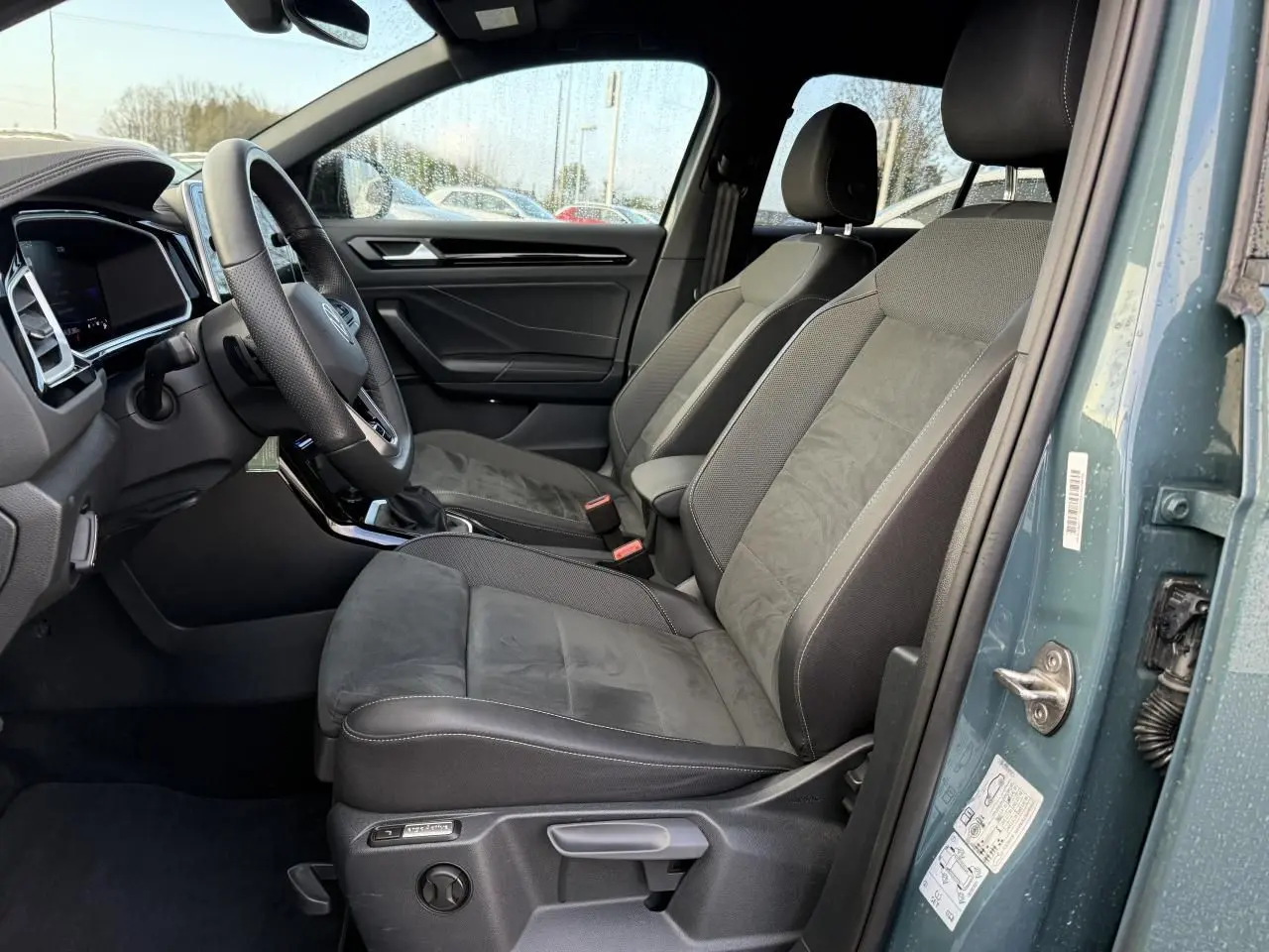 Vue intérieure côté conducteur du Volkswagen T-Roc 2025 bleu, sièges avant Ergoactive en tissu et alcantara gris.