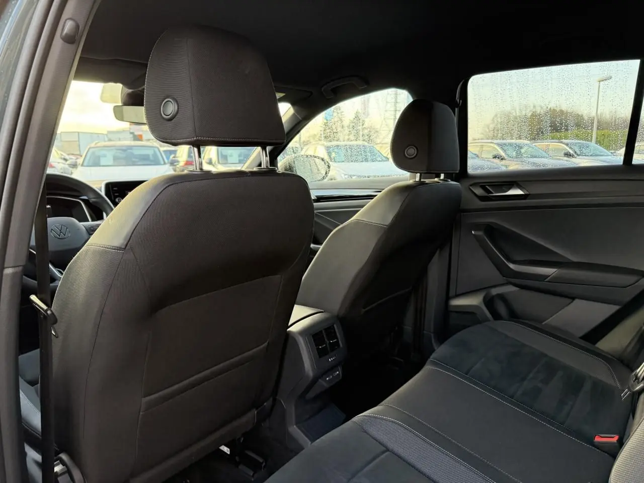 Vue intérieure arrière du Volkswagen T-Roc 2025, sièges noirs avec surpiqûres et détails tissu Alcantara.