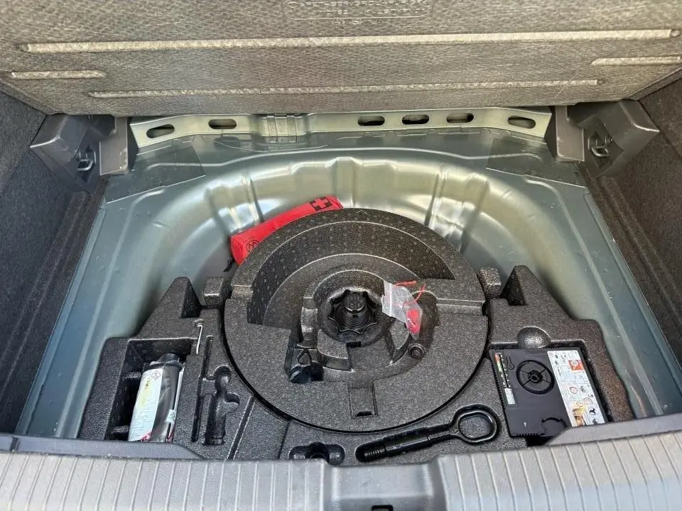 Coffre ouvert du Volkswagen T-Roc 2025 montrant le rangement sous plancher avec kit de dépannage et outils.