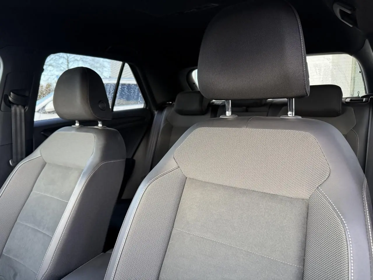 Gros plan sur les sièges avant gris du Volkswagen T-Roc 2025 avec appuis-tête et intérieur sombre.