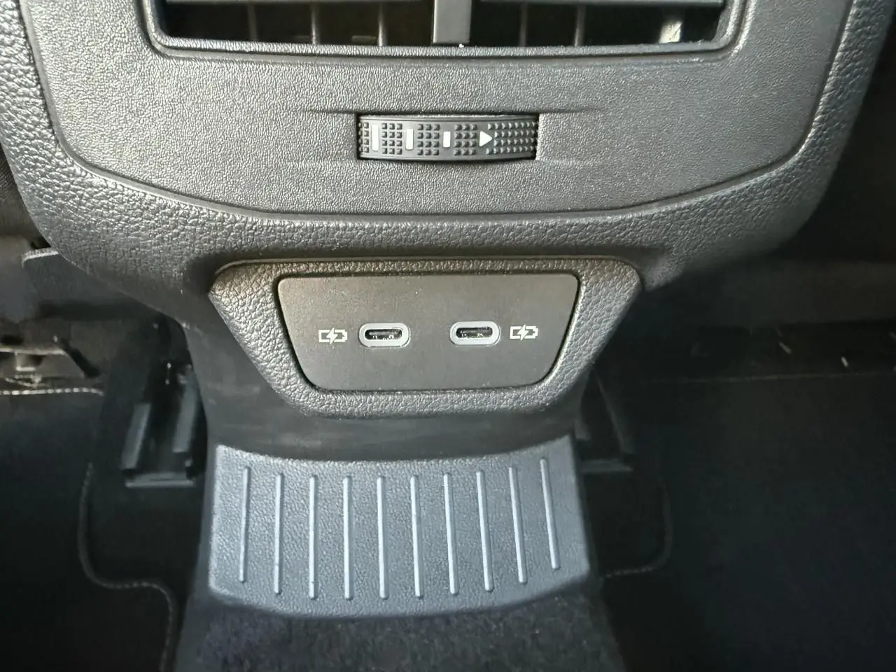 Gros plan sur la console arrière noire du Volkswagen T-Roc 2025 avec deux ports USB-C visibles.